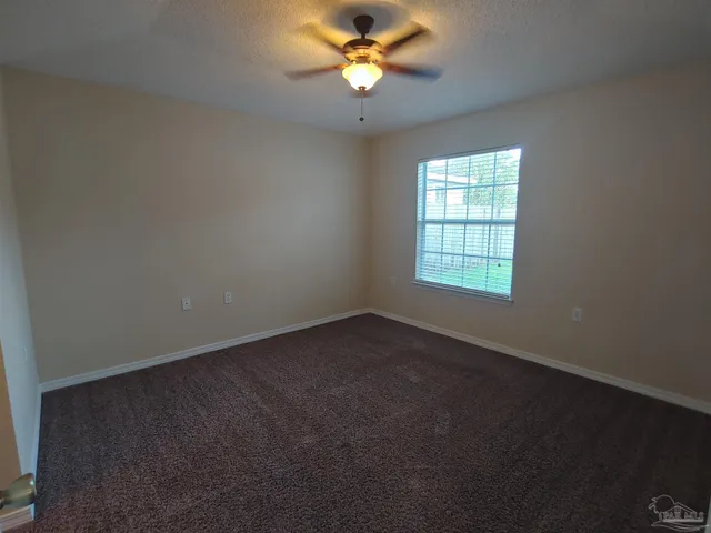 an empty room with a window and a fan