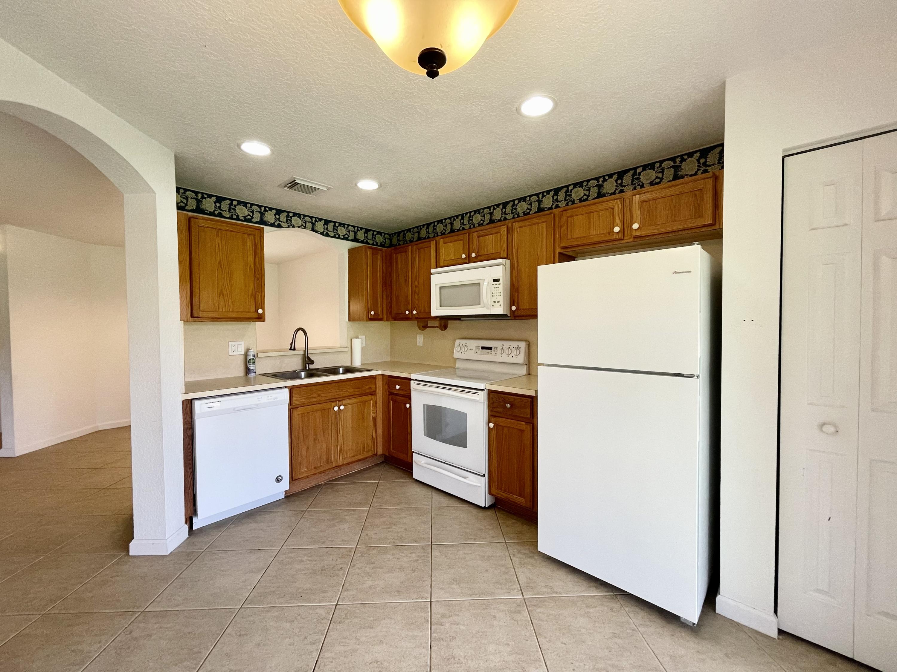 6204 Sandy Bank Terrace West Palm Beach, FL 33407 - Photo 5 of 37 a large kitchen with a sink a refrigerator and a stove top oven