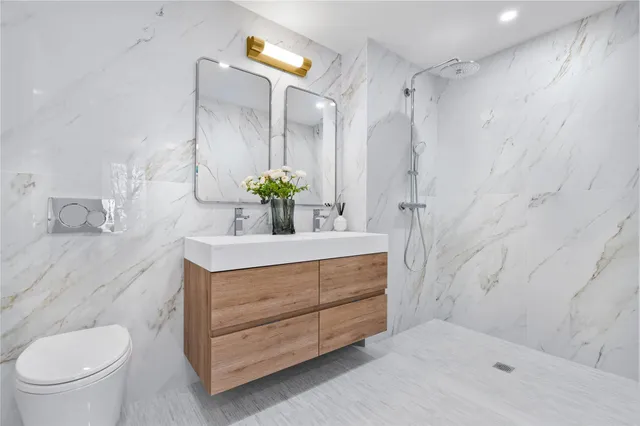 a bathroom with a granite countertop sink a toilet and shower