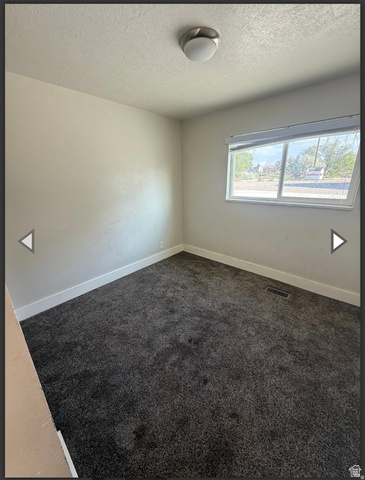 106 East Richelman Lane Wellington, UT 84542 - Photo 3 of 35 Empty room featuring dark carpet and a textured ceiling