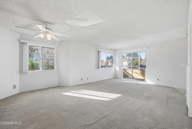 an empty room with windows and ceiling fan