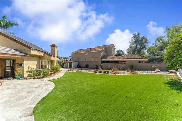 a view of a house with a big yard potted plants and large tree