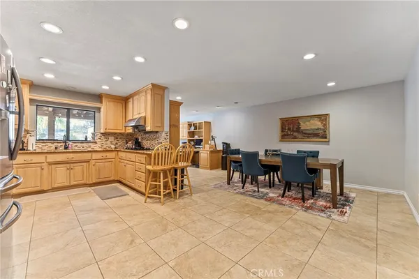 a very nice looking open dining room with kitchen island granite countertop a large window and a sink