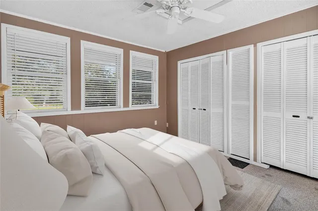 a bedroom with a large bed and a chandelier fan