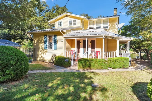 a view of a white house with large windows and a table and chairs in a yard