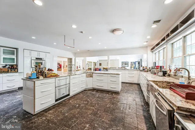 a large kitchen with kitchen island granite countertop a large counter top stainless steel appliances and a window