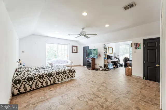 a living room with a bed furniture flat screen tv and kitchen view