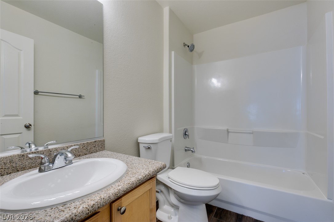 200 Luninborg Street Henderson, NV 89074 - Photo 16 of 40 A well-appointed bathroom features a practical tub-shower combination, a vanity with granite counters, and wood-look flooring.