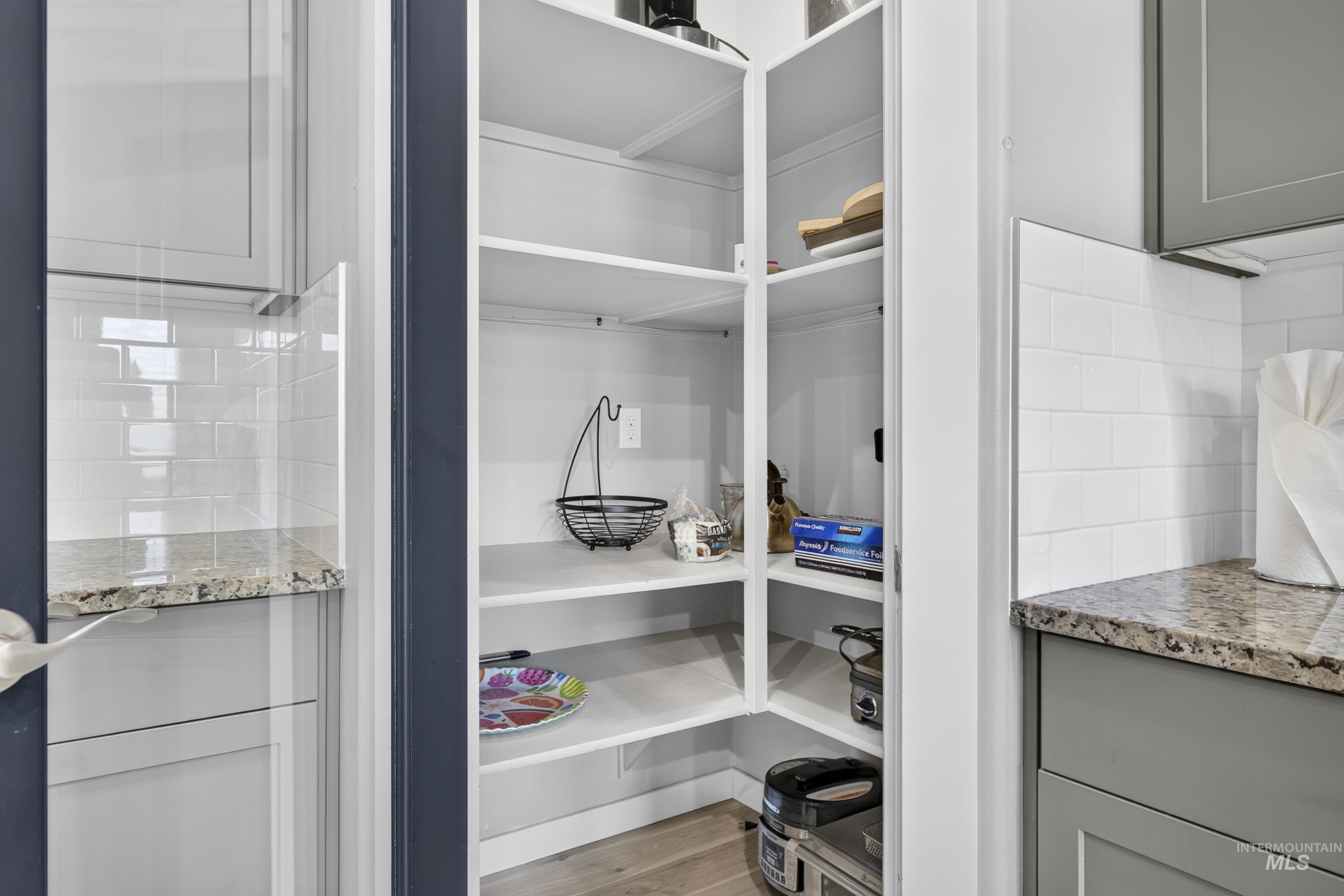 132 Mores Creek Rim Road Boise, ID 83716 - Photo 13 of 44 Built-in pantry shelving, white subway tile backsplash, light-colored granite-style countertop, and grey lower cabinetry