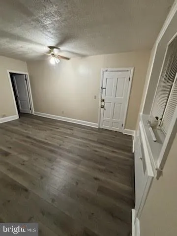 a view of an empty room with wooden floor and a ceiling fan