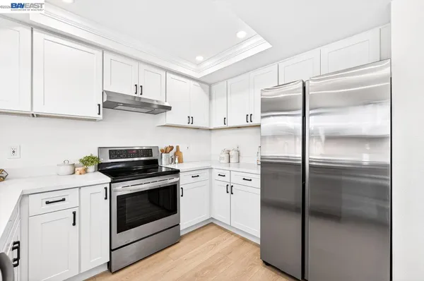 a kitchen with cabinets stainless steel appliances and wooden floor