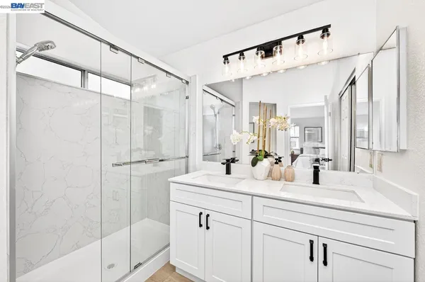 a bathroom with a double vanity sink mirror and shower