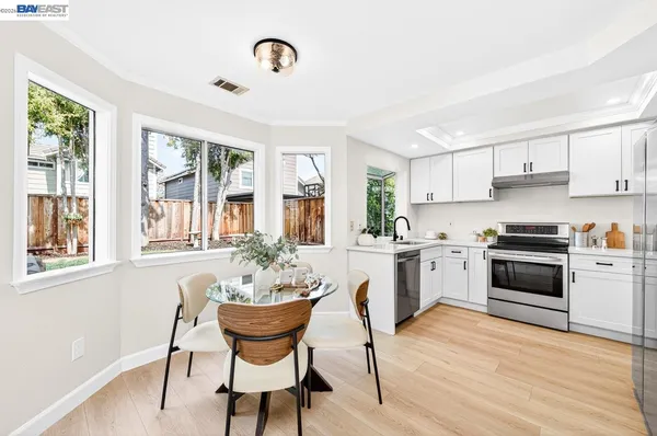 a kitchen with a stove a sink dishwasher a dining table and chairs with wooden floor
