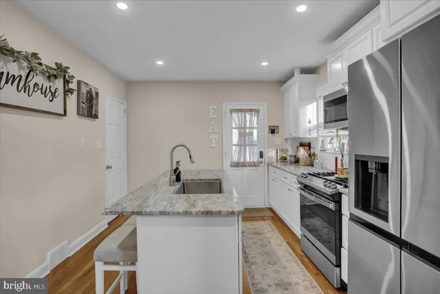 a kitchen with granite countertop a sink white cabinets and stainless steel appliances