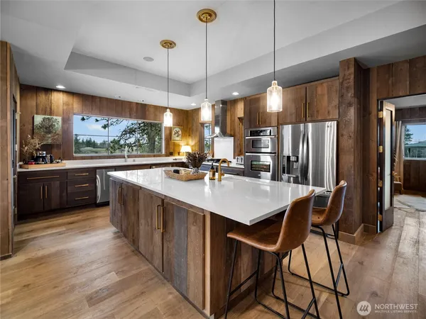 a kitchen with stainless steel appliances a sink a counter top space a large window and stainless steel appliances