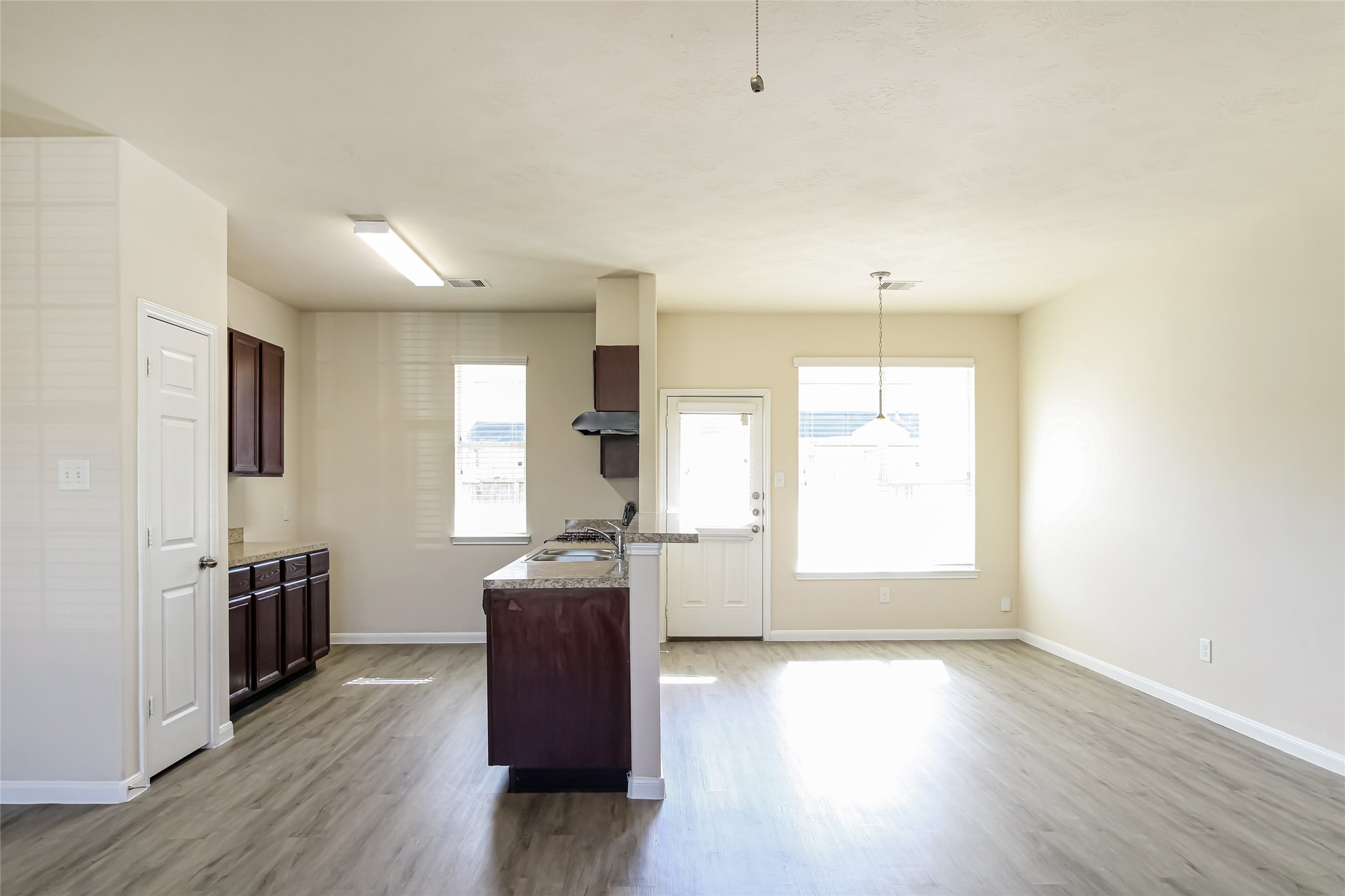 12406 Roy Mix Bohn Lane Houston, TX 77044 - Photo 5 of 16 a kitchen with granite countertop a stove a sink wooden floor and white cabinets