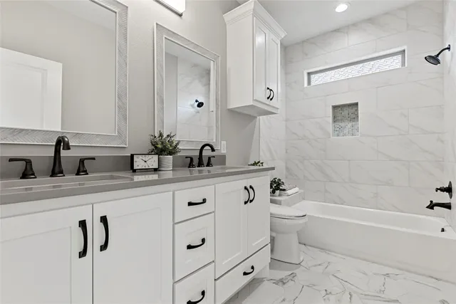 a bathroom with a double vanity sink a toilet a mirror and shower