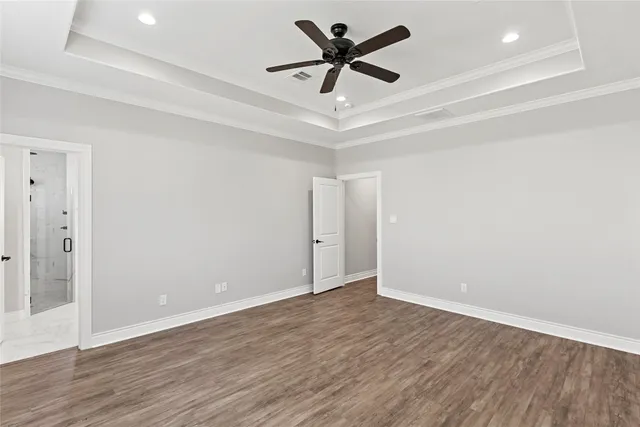an empty room with wooden floor and ceiling fan
