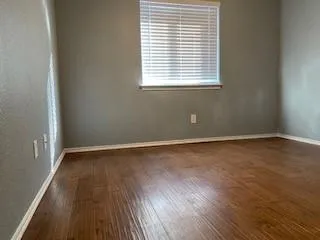 an empty room with wooden floor chandelier fan and windows