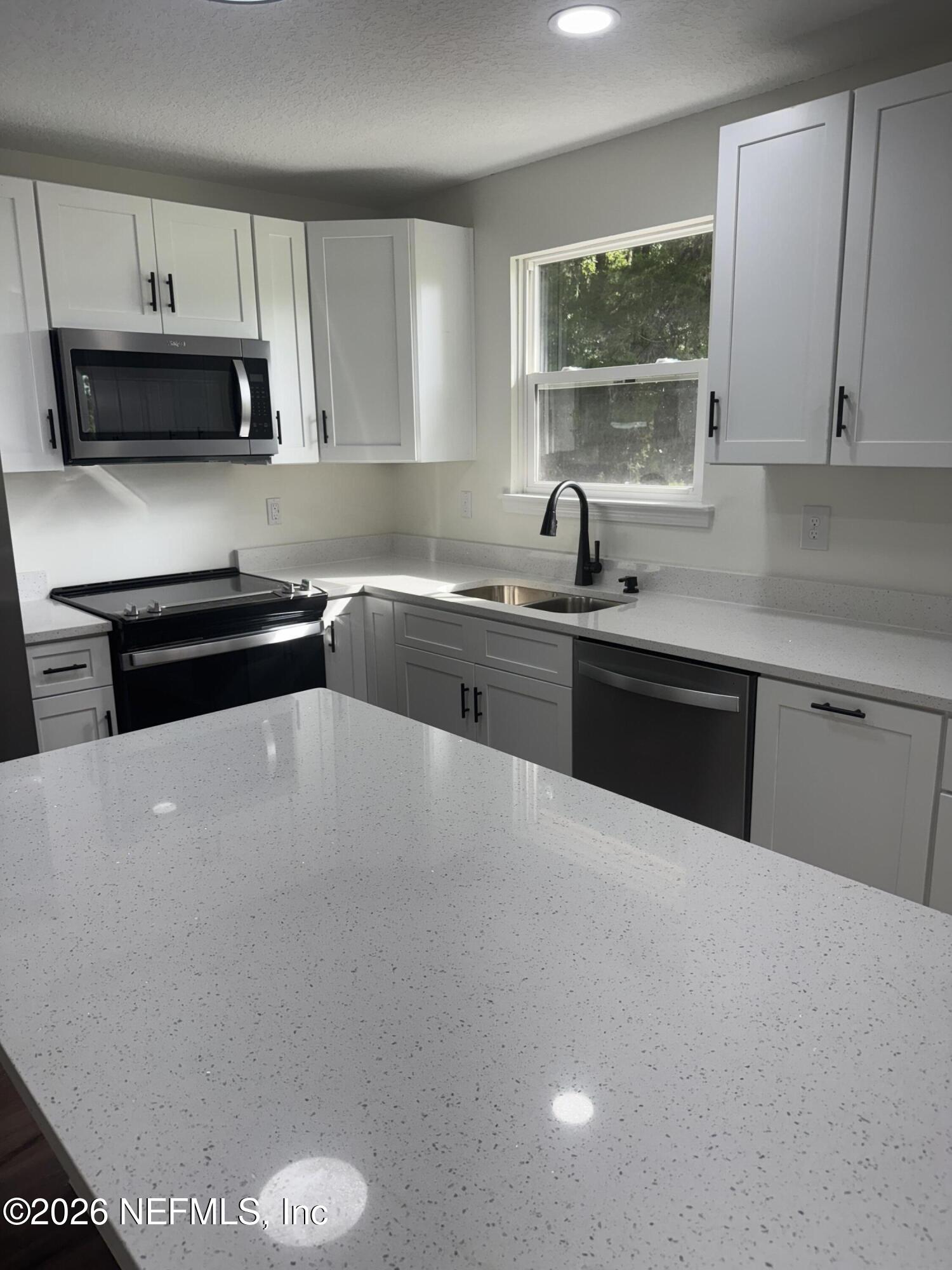 5202 Southwest 155th Street Starke, FL 32091 - Photo 2 of 13 a kitchen with stainless steel appliances a sink a stove a microwave a counter top space and cabinets