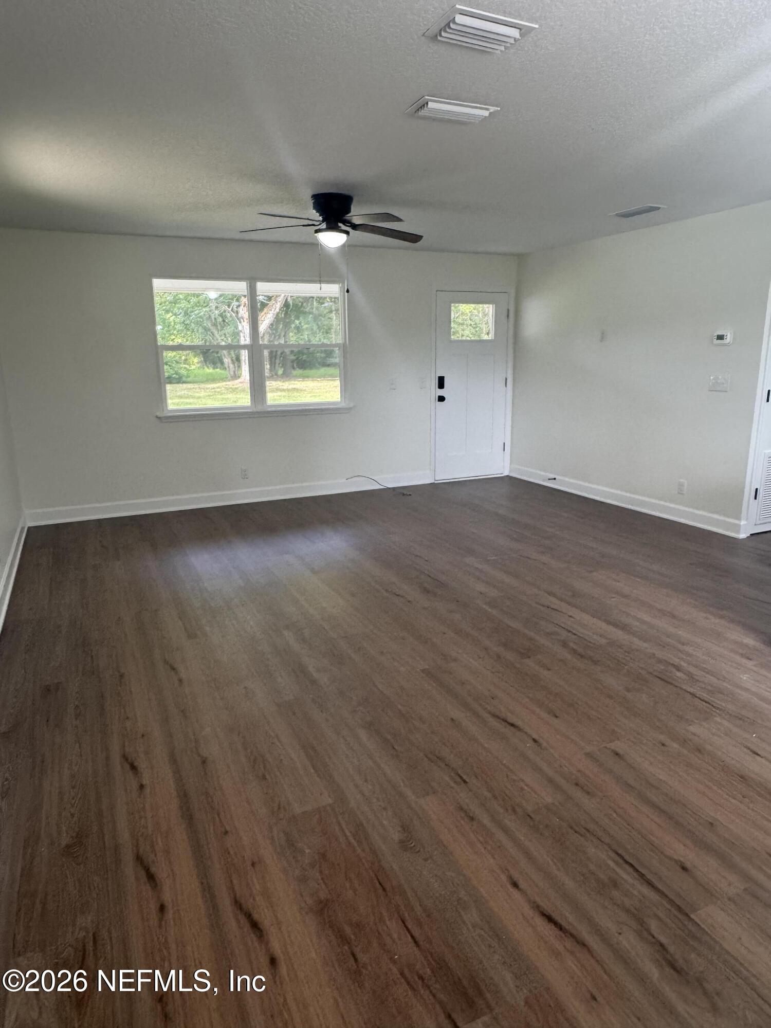 5202 Southwest 155th Street Starke, FL 32091 - Photo 8 of 13 an empty room with wooden floor white walls and windows
