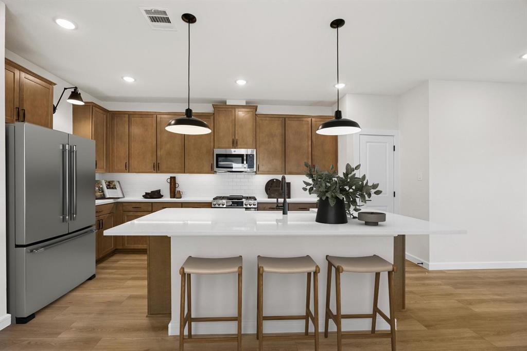 1317 Richardson Street Howe, TX 75459 - Photo 3 of 24 a kitchen with kitchen island a stove a chandelier and refrigerator