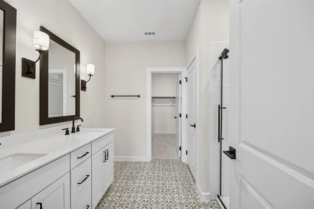 a spacious bathroom with a double vanity sink a mirror and a shower
