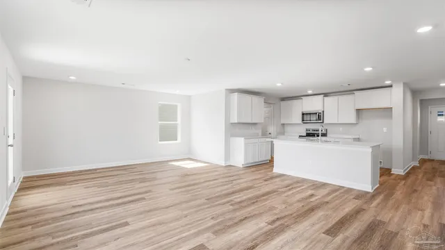 a view of a kitchen with white cabinets stainless steel appliances and window