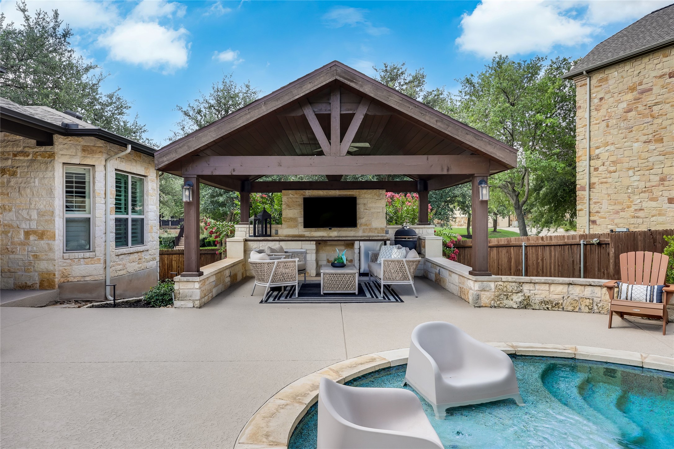 401 Bluff View Road Cedar Park, TX 78613 - Photo 5 of 40 An inviting covered patio featuring an outdoor kitchen and a poolside lounge area, perfect for entertaining.