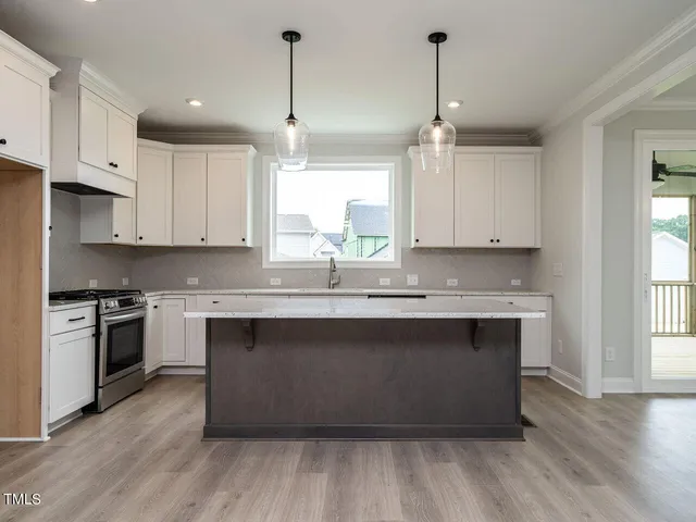 a kitchen with stainless steel appliances granite countertop a sink a stove a refrigerator and island with wooden floor