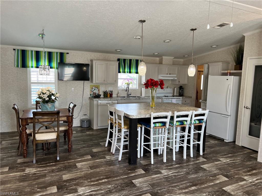 6 Cannes Drive Naples, FL 34112 - Photo 6 of 21 a kitchen with stainless steel appliances granite countertop a dining table chairs refrigerator and microwave