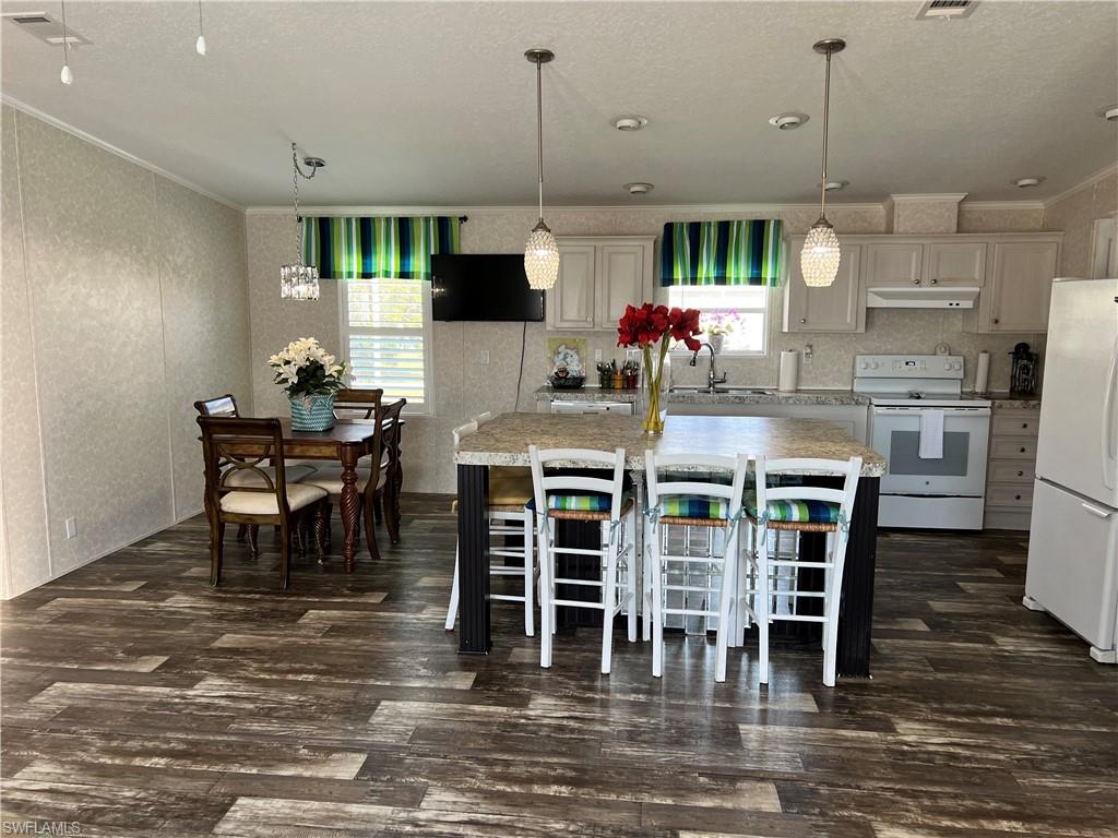 6 Cannes Drive Naples, FL 34112 - Photo 9 of 21 a kitchen with stainless steel appliances kitchen island granite countertop a table and chairs in it