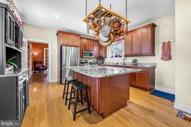 a kitchen with stainless steel appliances granite countertop a stove a sink dishwasher and a refrigerator with wooden floor