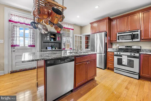 a kitchen with stainless steel appliances granite countertop a stove refrigerator sink and microwave