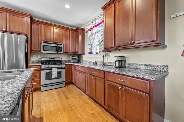 a kitchen with stainless steel appliances granite countertop wooden cabinets a stove top oven a sink and dishwasher