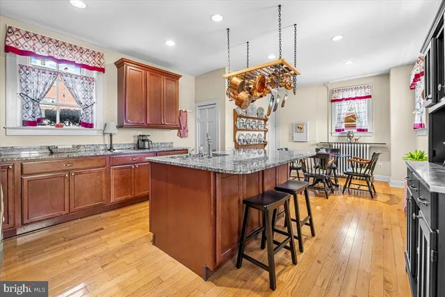 a kitchen with stainless steel appliances granite countertop a kitchen island hardwood floor sink stove dining table and chairs