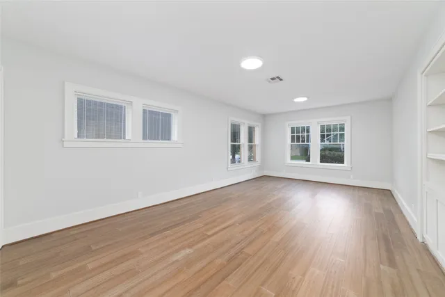 a spacious bedroom with a bed a couch and a flat tv screen on dresser