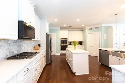 a large kitchen with stainless steel appliances kitchen island a large counter top a stove a sink and a refrigerator