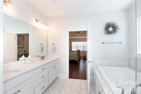a spacious bathroom with a tub sink and mirror