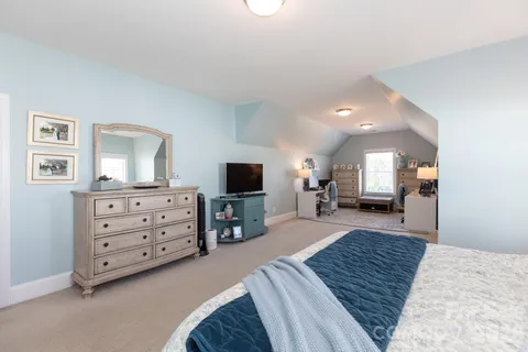 a bedroom with a bed a couch and a flat screen television