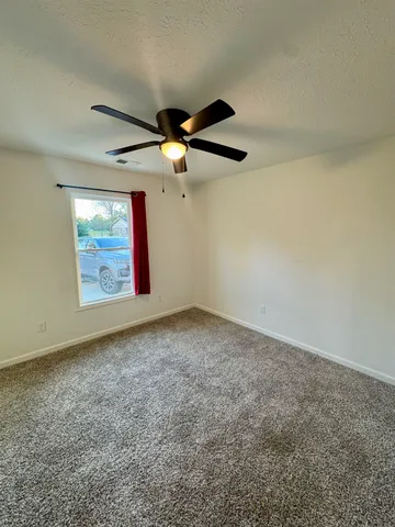 an empty room with windows and fan
