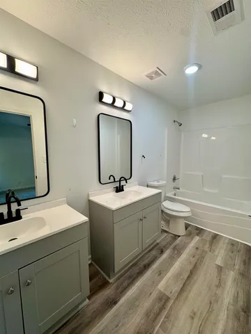 a bathroom with a double vanity sink mirror and bathtub