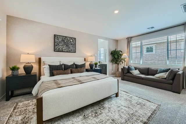 a spacious bedroom with a bed a couch and potted plant with the wooden floor