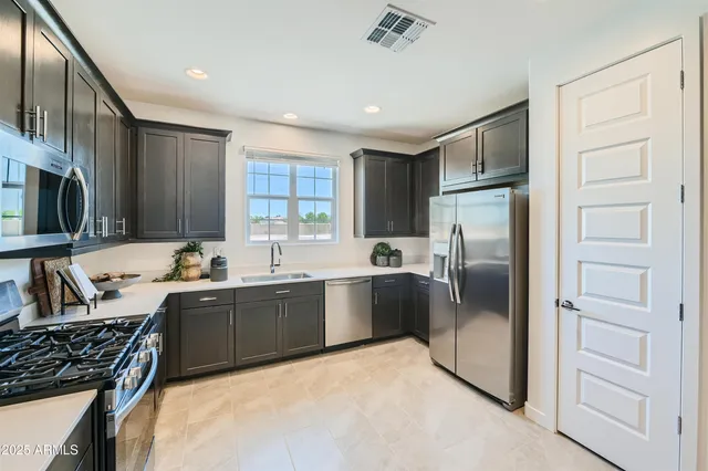 a kitchen with stainless steel appliances granite countertop a sink stove refrigerator and cabinets