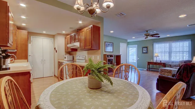 a kitchen with stainless steel appliances kitchen island granite countertop a table chairs in it and a window