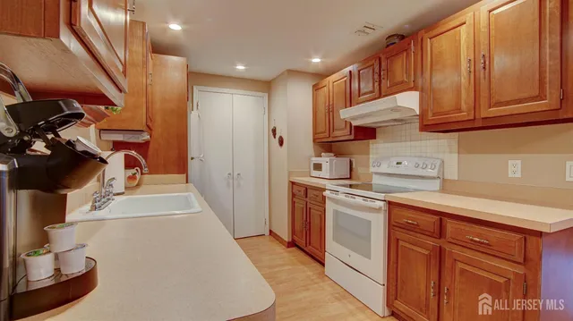 a kitchen with stainless steel appliances granite countertop a refrigerator a sink dishwasher and white cabinets with wooden floor