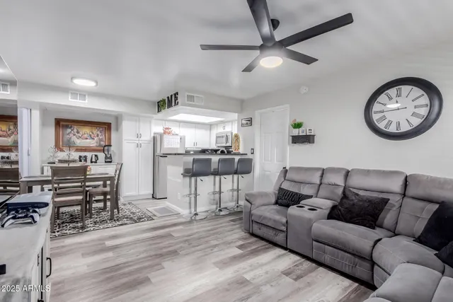 a living room with furniture a clock and a ceiling fan