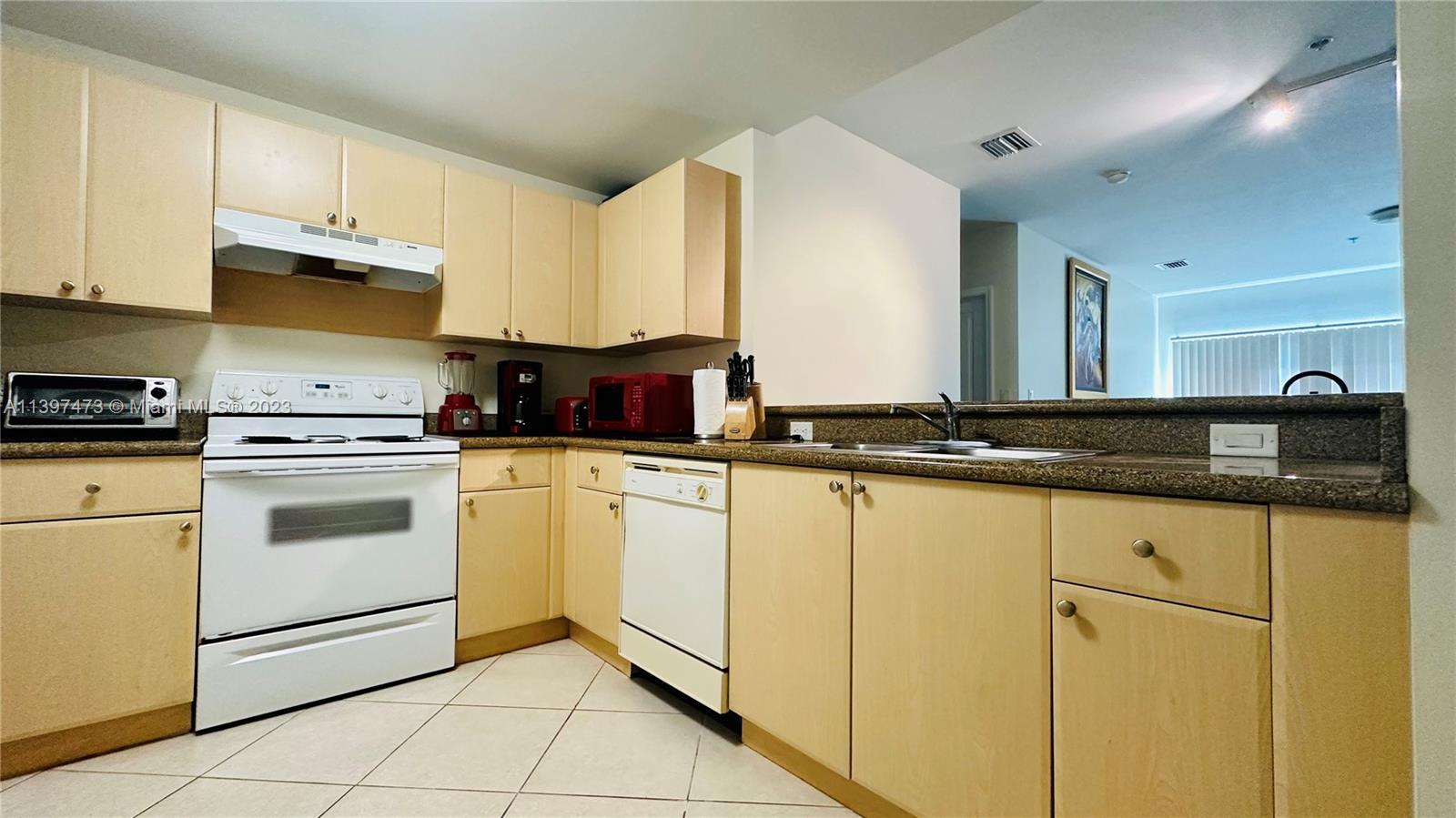 2280 Southwest 32nd Avenue, Unit 315 Miami, FL 33145 - Photo 7 of 21 a kitchen with granite countertop white cabinets and white appliances