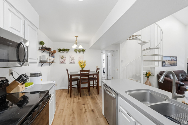 650 South Main Street, Unit 3304 Bountiful, UT 84010 - Photo 9 of 22 Kitchen and dining area featuring stainless steel appliances, wood-finish flooring, a double basin sink, and a spiral staircase