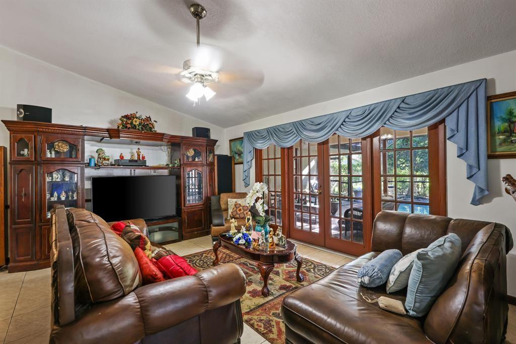 5172 Northwest 84th Road Coral Springs, FL 33067 - Photo 11 of 24 a living room with furniture a flat screen tv and a floor to ceiling window